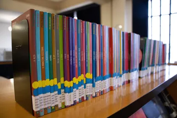 Livros coloridos estão dispostos em uma prateleira.