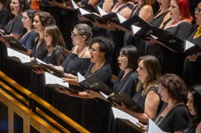Foco do naipe de sopranos do Coro da Osesp cantando no palco da Sala São Paulo.