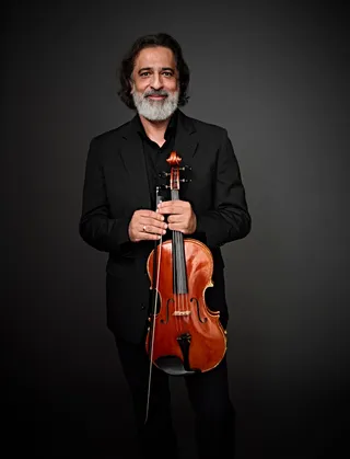 David Marques is a white man with a white beard and chin-length brown hair. He is wearing black clothing and holding a viola.