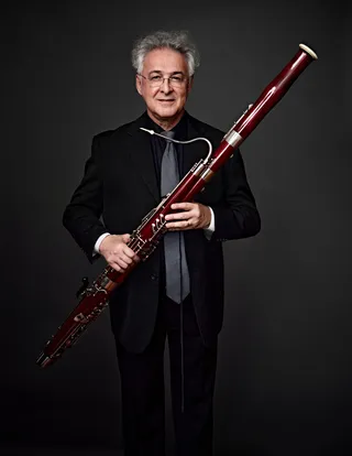 Francisco Formiga é um homem branco, com cabelos grisalhos e óculos. Ele está usando uma gravata cinza, uma camisa preta e um blazer preto.