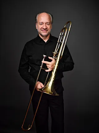 Wagner Polistchuk is a bald white man wearing a black shirt. He is holding a trombone.