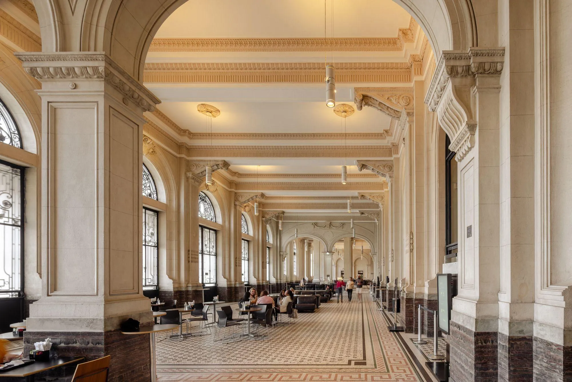 Hall Principal da Sala São Paulo, com paredes em tons de bege e grandes portões metálicos. Ao centro, estão alguns sofás.