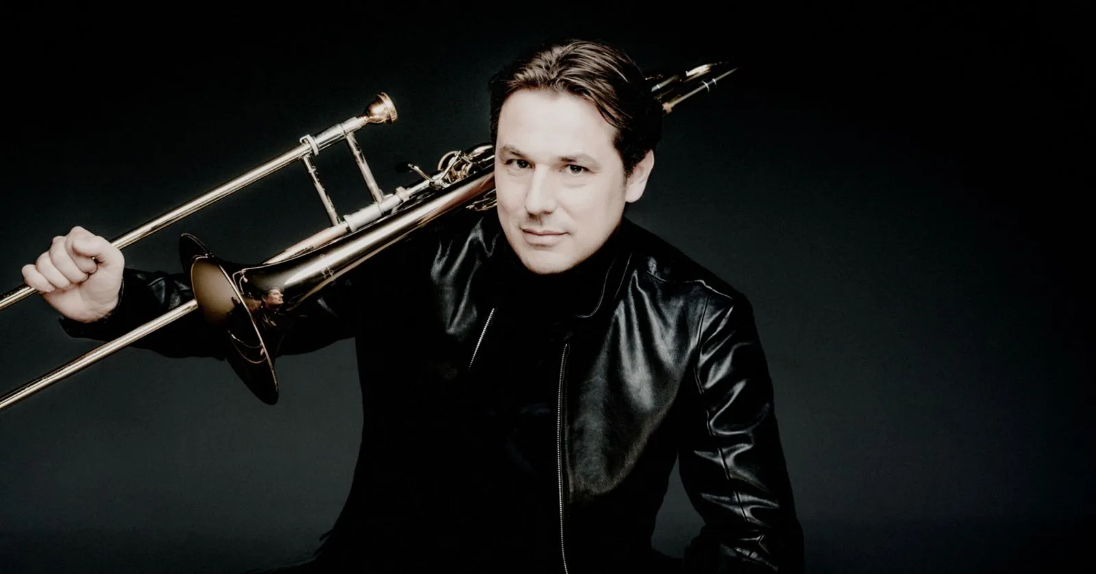 Jörgen van Rijen é um homem branco, de cabelos castanhos. Ele apoia o queixo em um trombone.