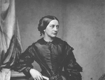 Clara Schumann usa um vestido preto e cabelos presos em um fundo neutro. Ela olha para o lado.
