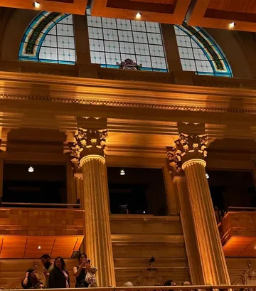 A foto mostra a Sala de Concertos iluminada, com os vitrais aparecendo.