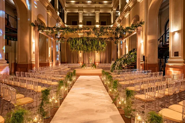 Foyer decorado para uma festa, com cadeiras e muitas plantas.