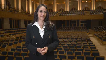 Foto de Simone. Ela tem cabelos lisos, longos e escuros. Veste camisa branca e um blazer preto com botões dourados.
